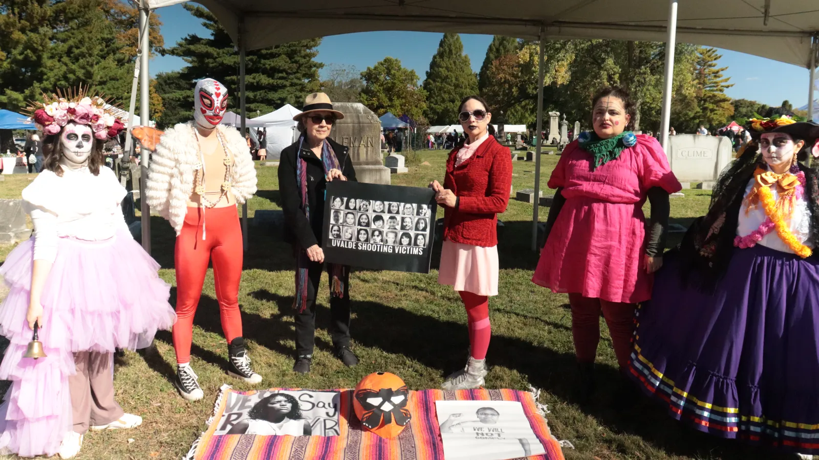 Five people standing around a blanket